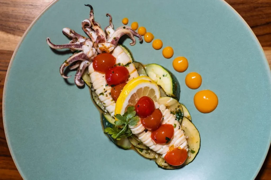 Pan-fried baby squid with garlic, herbs, and cherry tomatoes served at KAIO Beach Front Restaurant.