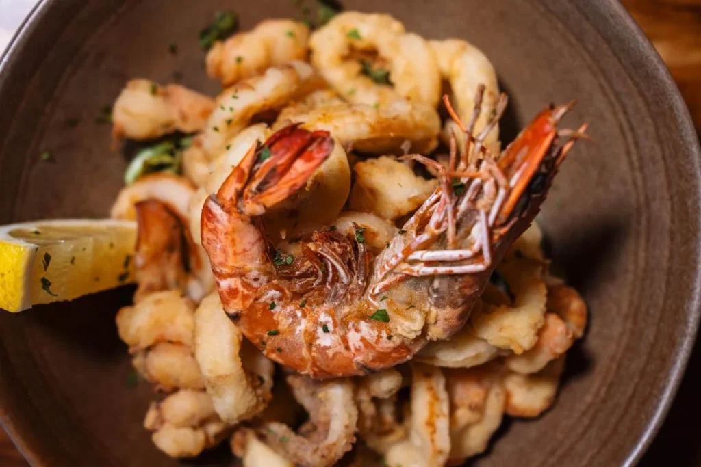 Golden crispy fried calamari rings and prawn platter with lemon at KAIO Beach Front Restaurant.