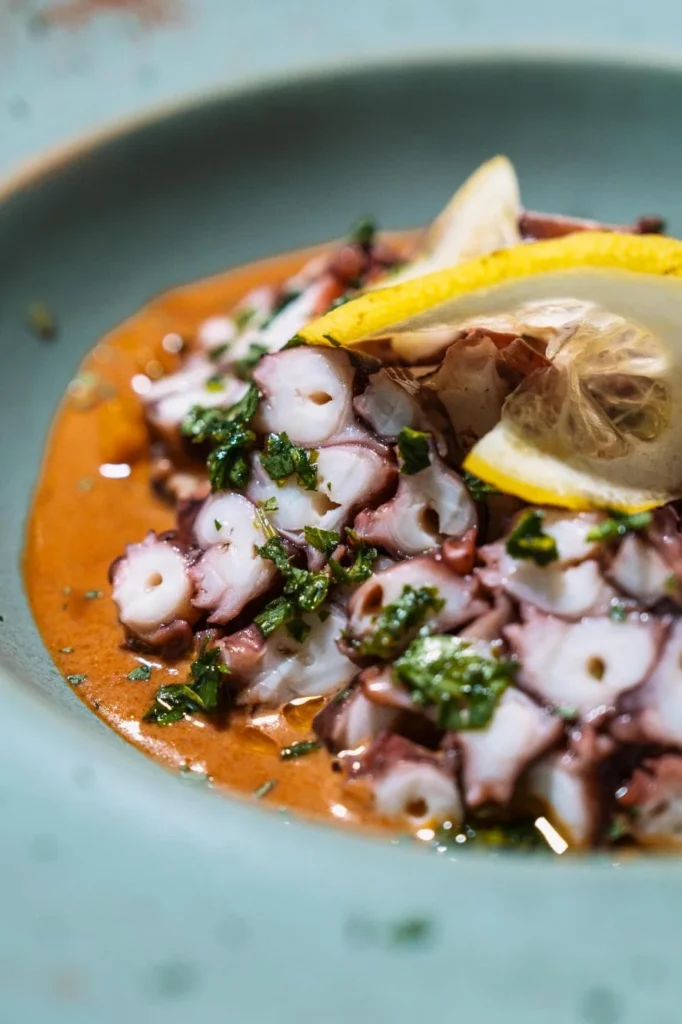 Close-up view of octopus carpaccio drizzled with citrus vinaigrette at KAIO Beach Front Restaurant.