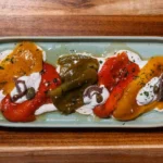 Sweet roasted peppers topped with marinated anchovies and garlic served at KAIO Beach Front.