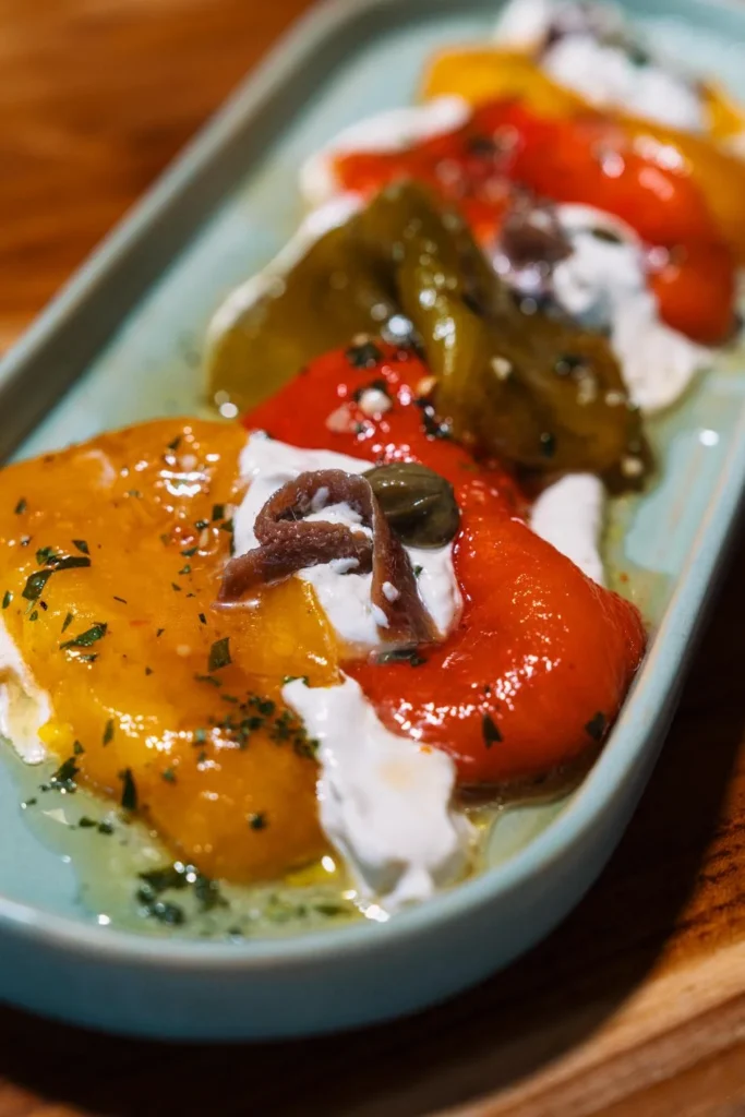 Close-up roasted peppers topped with marinated anchovies and garlic served at KAIO Beach Front.