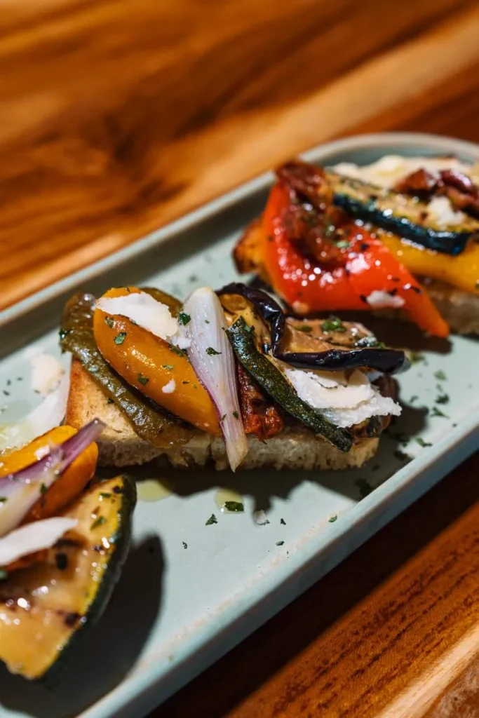 Close-up toasted bruschetta topped with grilled vegetables and shaved Parmesan at KAIO Beach Front.