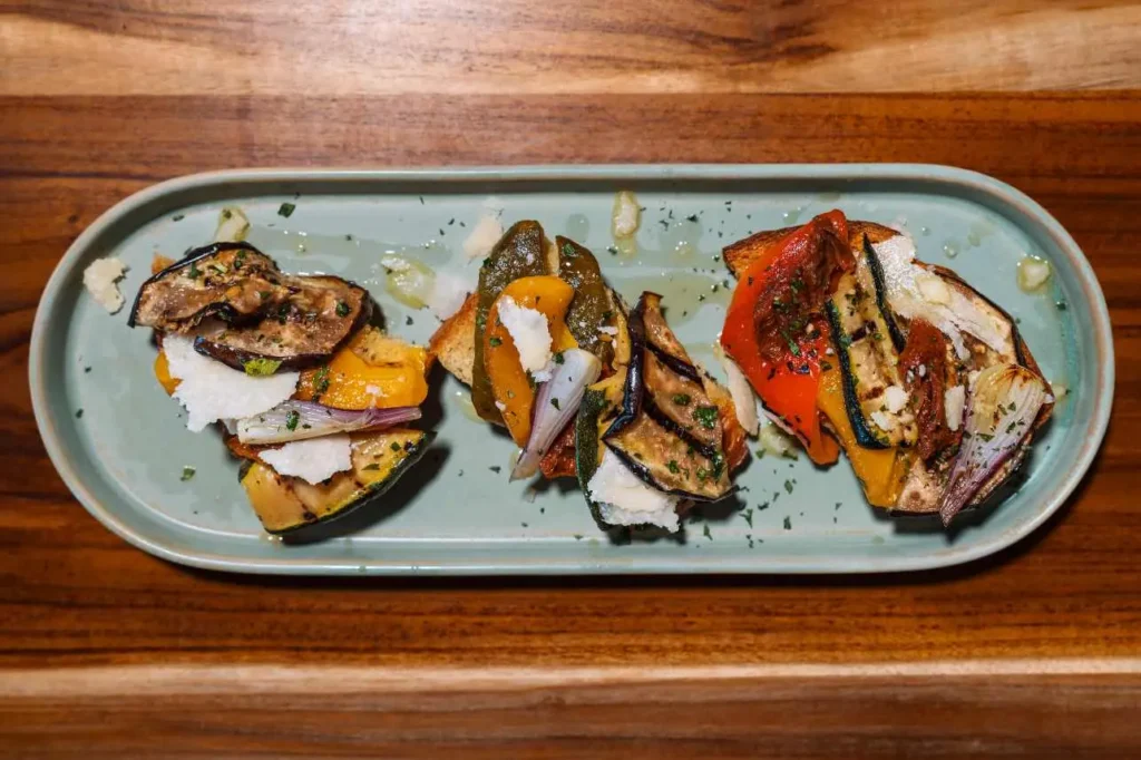 Toasted bruschetta topped with grilled vegetables and shaved Parmesan at KAIO Beach Front.
