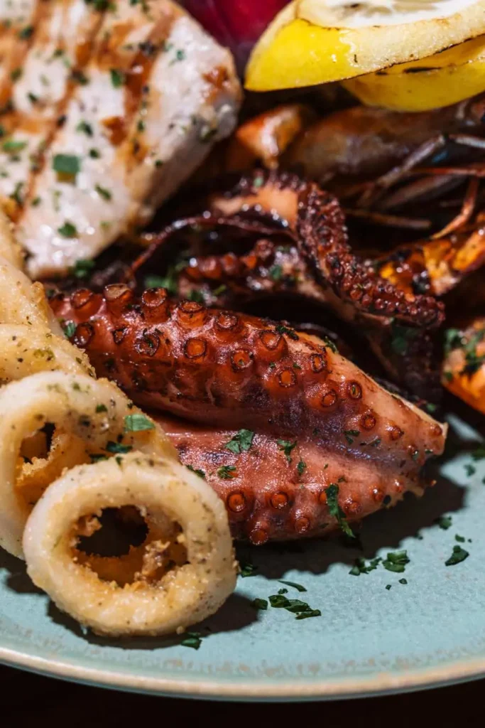Seafood tower platter featuring grilled fish, calamari, octopus, and fresh lemon.